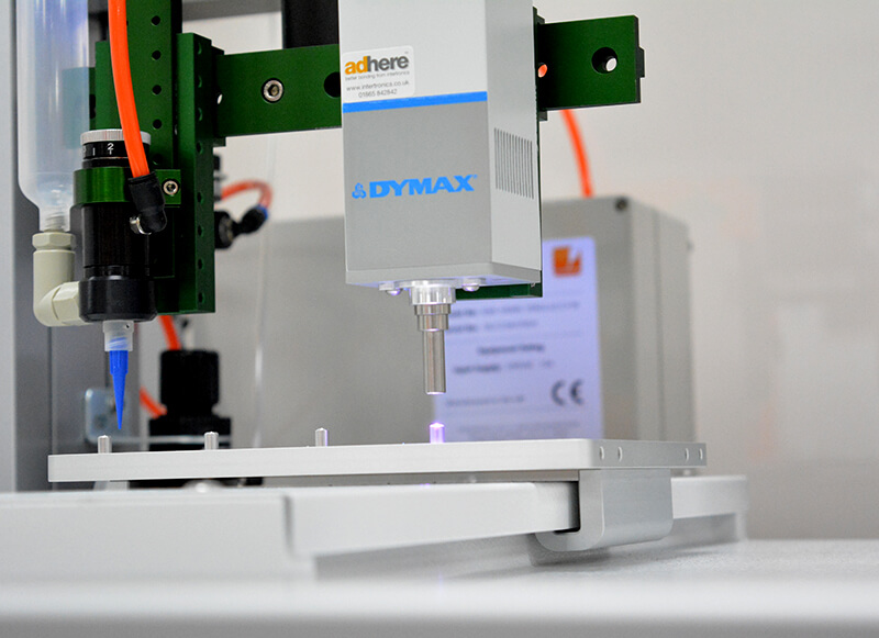 Automated dispensing and UV light curing system