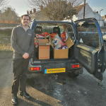 James stands proudly next to a vehicle full of foodbank donations