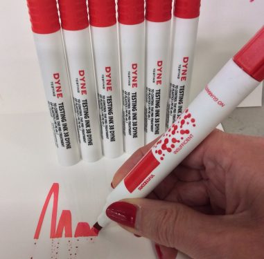 Dyne Testing Instant Dyne Pen 38 scribbling a red squiggle on a substrate to show treated versus untreated parts